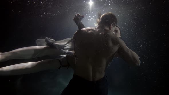 Young Sexy Woman in Lingerie is Alluring Brawny Man Underwater Floating Around His alt