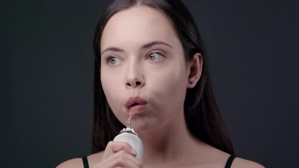 Young Brunette Woman Cleaning Her Teeth with Water Flosser alt