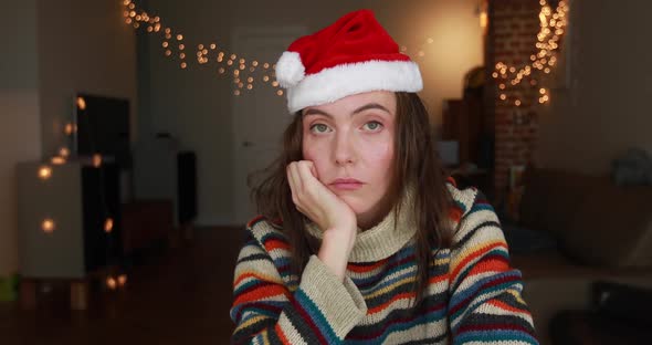 Bored Lady in Coloured Pullover and Red Christmas Hat Sits alt