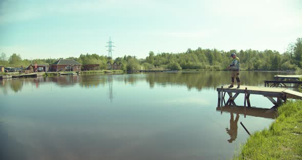 Man Fishing on Wooden Pier Near Lake