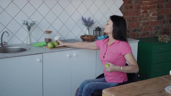Adult Woman in Wheelchair Cleaning Fresh Apple on Kitchen
