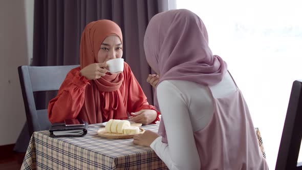 Young muslim working woman discussing with friend in coffee shop alt