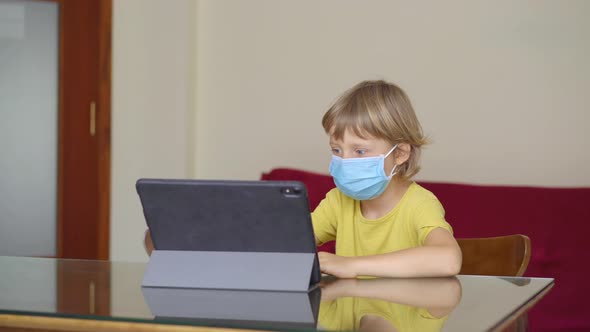 A Young Woman and Her Little Son Sit a Home During Quarantine and Study in the Internet School Using alt