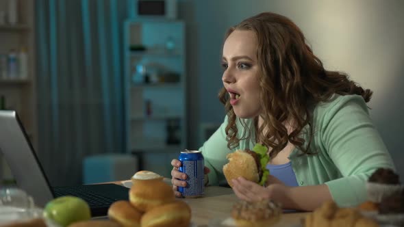 Chubby Girl Laughing at Movie on Laptop While Eating Burger and Drinking Soda, Stock Footage