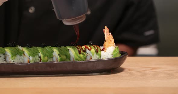 Skilled Chef Putting Sauce On Top Of Sushi Rolls Before Serving. Japanese Cuisine.  - close up shot alt