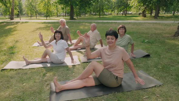 Female Coach Doing Yoga with Aged People Outdoors alt