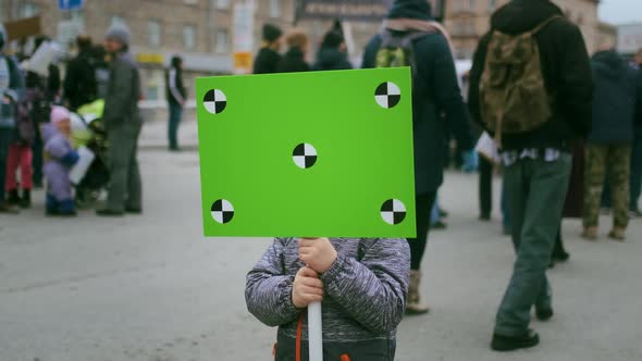 Smiling Boy with Green Mockup Banner Looks at Camera