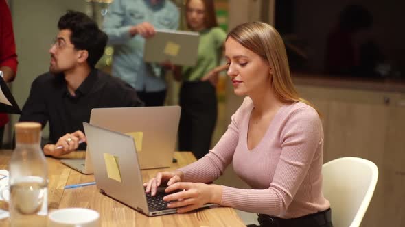 Tracking Shot of Focused Young Business Woman Sitting at Office Desk and Working on Laptop While alt
