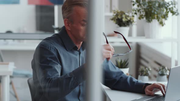 Handsome Businessman Posing for Camera with Smile at Office Desk alt