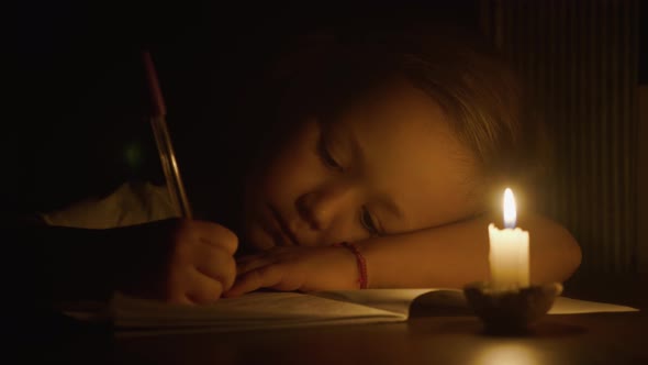 Closeup of Child Girl is Writing By Pen in Candlelight at Darken Room