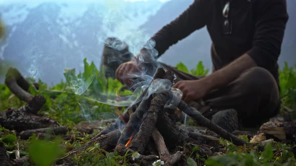 A Person Putting Some Tree Branches On A Campfire During Cold Morning - Close Up alt