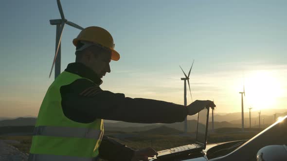 Technician Engineer in Wind Turbine Power Generator Station Checks the Status of the Turbines Using