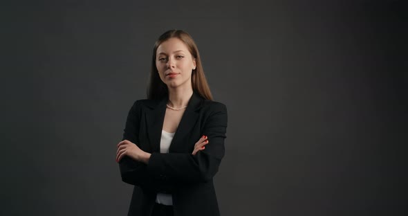 Confident Ambitious Business Woman in Black Suit Watches to the Camera Folded Hands Closed Pose alt