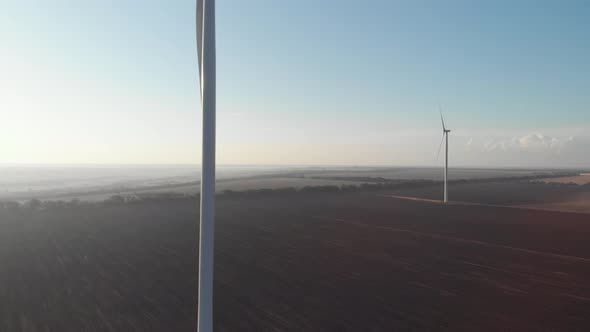 Wind turbines power plant tower aerial sunset view green energy. Wind mills rotating generating