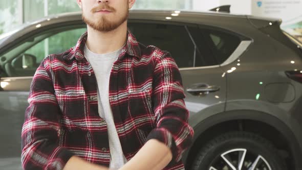 Cropped Shot of a Man Holding Out Car Keys To the Camera Posing at the Dealership
