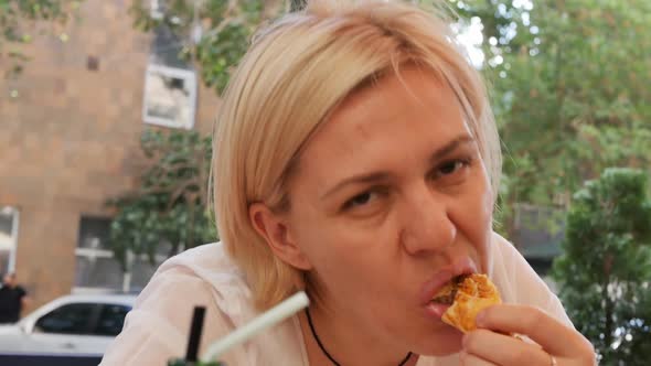 Caucasian Woman Eats Pide Holding a Piece in Her Hand and Bites Off with Her Teeth While Sitting in