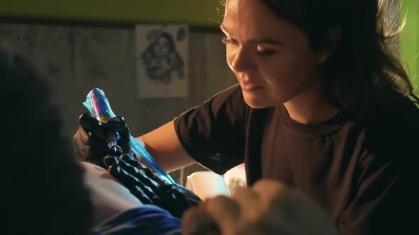 Tattooist Girl Fills with Machine Black Ink Paint in Bare Male Customers Chest