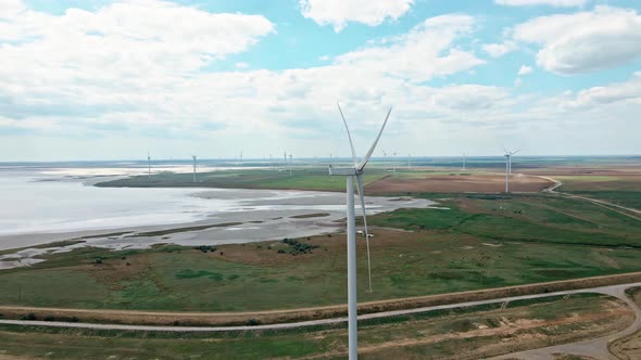 Drone Moving Around Wind Turbine with Wind Generators Farm on Background alt