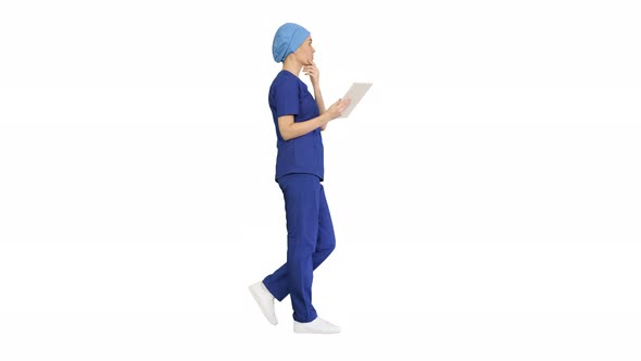 Young Woman Doctor or Nurse in Scrubs Using a Touchscreen Computer While Walking on White Background