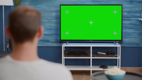 Over Shoulder View of Man Watching Movie on Tv with Green Screen Relaxing with Bowl of Popcorn alt