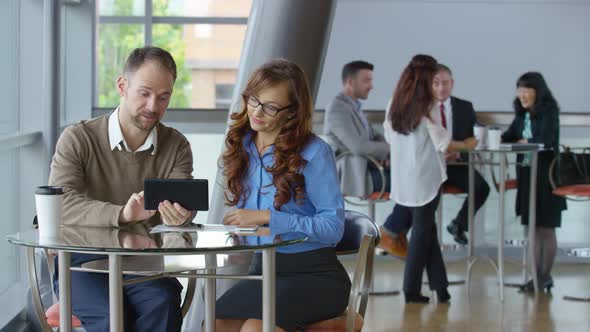 Two young business people use digital tablet