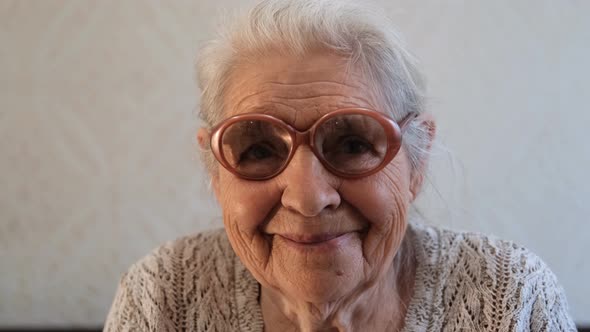 Slow Motion Portrait of a Happy Senior Woman with Gray Hair and Glasses.