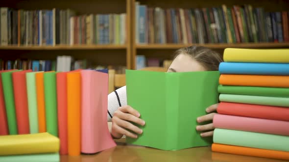 A Schoolgirl Is Hiding Behind a Book in the Library