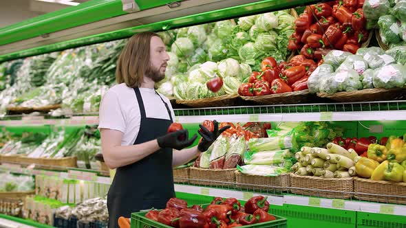 Man Replenishes Products on the Shelves Juggles Red Pepper Fruits Young Man Puts Paprika on a Shelf alt
