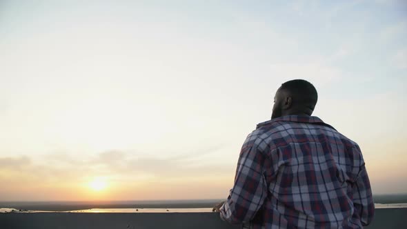 Back View of Afro-American Man Enjoying Sunset From Roof Top, Day Dreaming