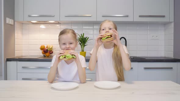 Twins Eating Burgers in Kitchen