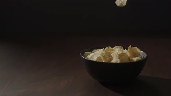 Slow Motion Man Take Organic Potato Chips From Black Bowl on Walnut Table