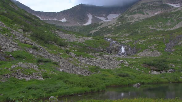 Lake in Mountain Valley. Stream on Side of Hill