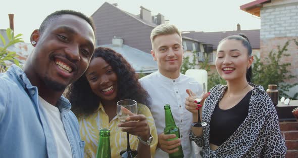 Friends Making Selfie During Party on the Terrace Overlooking at City Roofs at Summertime alt