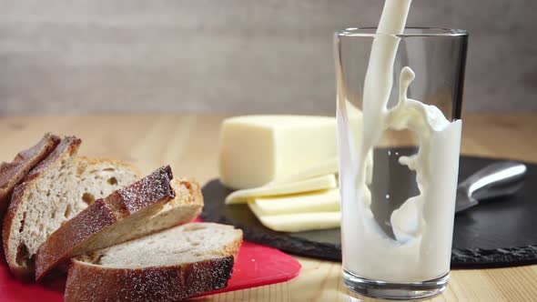 Milk is Poured Into a Glass and Cheese and Bread