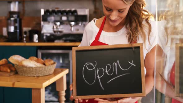 Smiling waitress holding a open sign board alt
