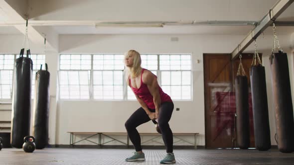 Fit caucasian woman working out with kettle bell at the gym alt