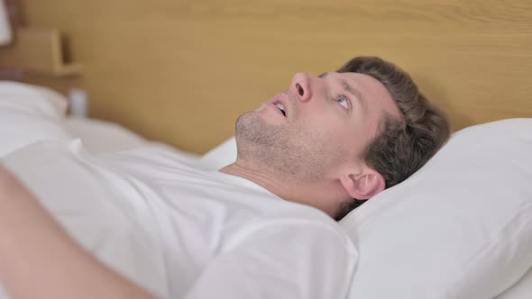 Shocked Young Man Wake Up From Sleep in Bed alt