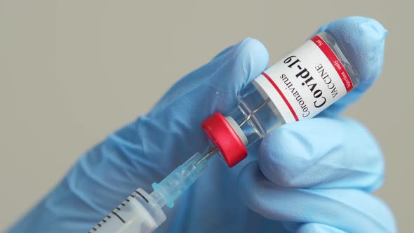 Doctor Holding Coronavirus Vaccine and Syringe to Prevent COVID19 Infection alt