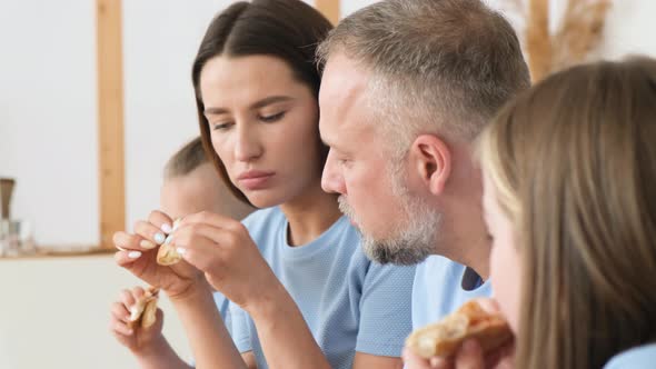 Young Family Deliciously Eating Italian Pizza Sitting in the Kitchen at the Table alt