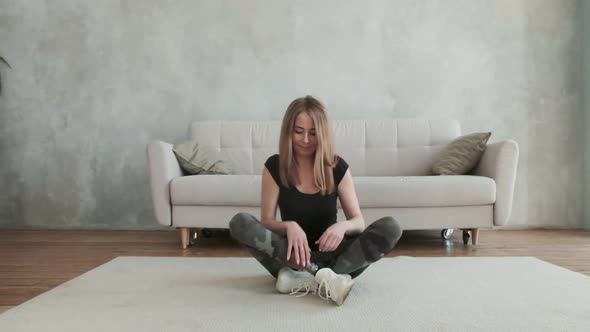 female sits on floor in lotus position with her artificial leg bent and relaxes