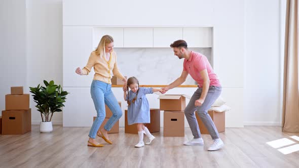 Amazed family parents and preschooler daughter dance on new apartment floor alt
