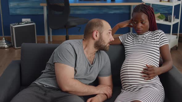 Young Interracial Parents Sitting Together on Couch alt