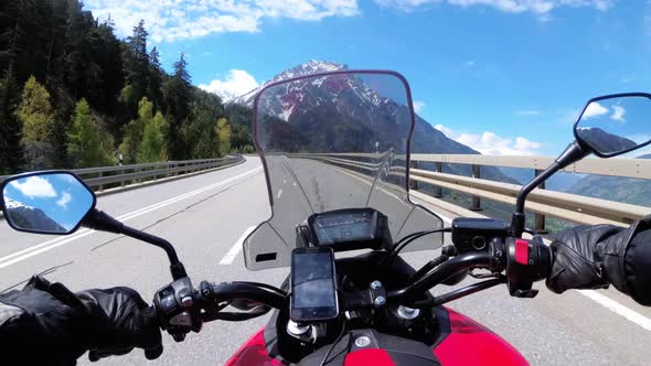 Motorcyclist Rides on Beautiful Landscape Mountain Road Near Snowy Switzerland Alps