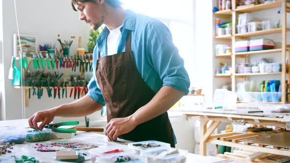 Young master in uniform considering art thumbnails on the desk alt
