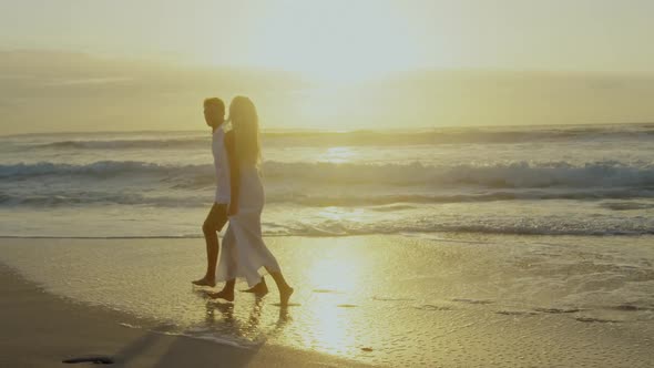 Couple walking together on beach during sunset 4k