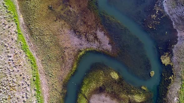 Top down aerial view of colorful river flowing into lake alt