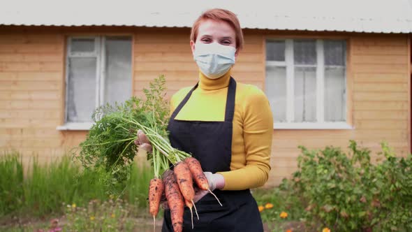 Happy Young Farmer in Medical Mask Holds Organic Vegetables Looking at the Camera and Smiling alt