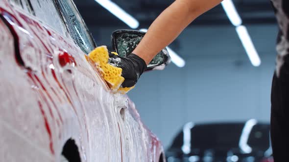 Auto Cleaning Service  Man Cleaning the Car Surface with a Yellow Sponge alt