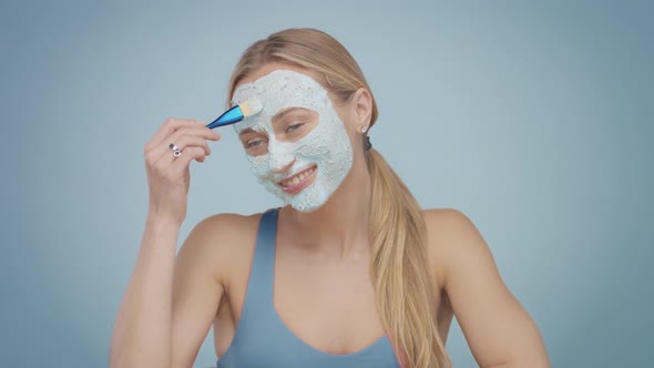 Blonde Model in Studio Makes a Cleansing Facial Mask