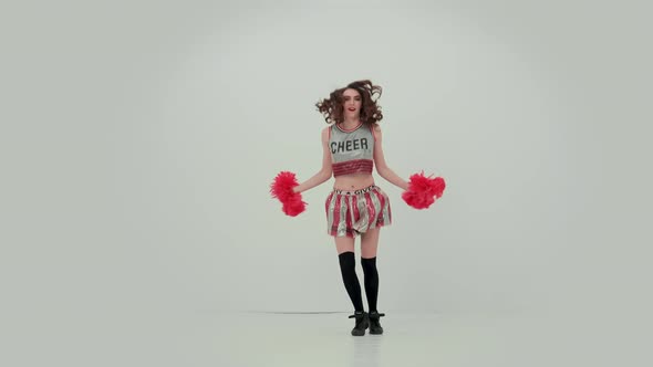 Sportive Girl Dancing a Jubilant Dance with Pompoms in the Studio on a White Background alt